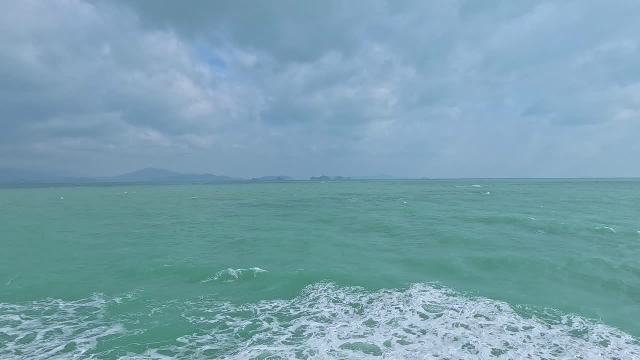 Calm turquoise waters under a cloudy sky, captured from a moving boat near Koh Samui, Thailand