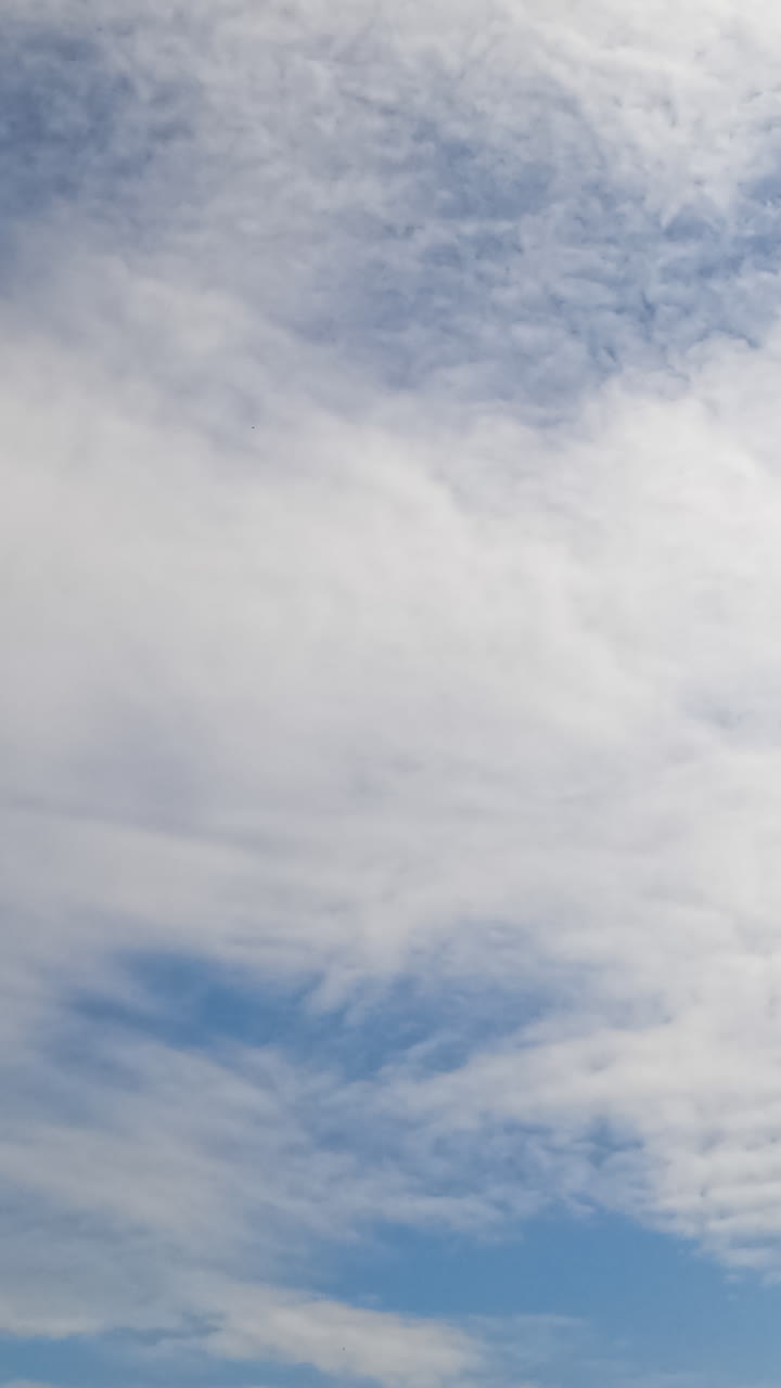 White spindrift cloudscape covering the summer skies. Lovely view of light clouds in the horizon. Timelapse. Vertical video