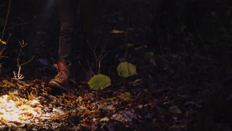 Legs-Of-A-Woman-In-Boots-Walking-Along-A-Forest-Trail-Lit-By-The-Light-Of-A-Flashlight
