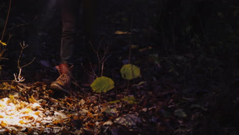 Beine-Einer-Frau-In-Stiefeln,-Die-Einen-Waldweg-Entlanggeht,-Der-Vom-Licht-Einer-Taschenlampe-Beleuchtet-Wird