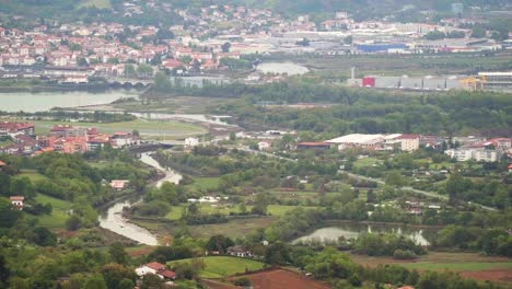 wide view of the bidasoa river with the international bridge connecting irun, spain and hendaye, france, surrounded by residential areas and greenery on an overcast day