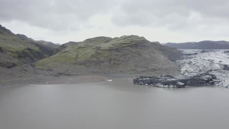 vista aérea de drones sobre la laguna en el glaciar solheimajokull, en islandia - reversa, disparo de drones
