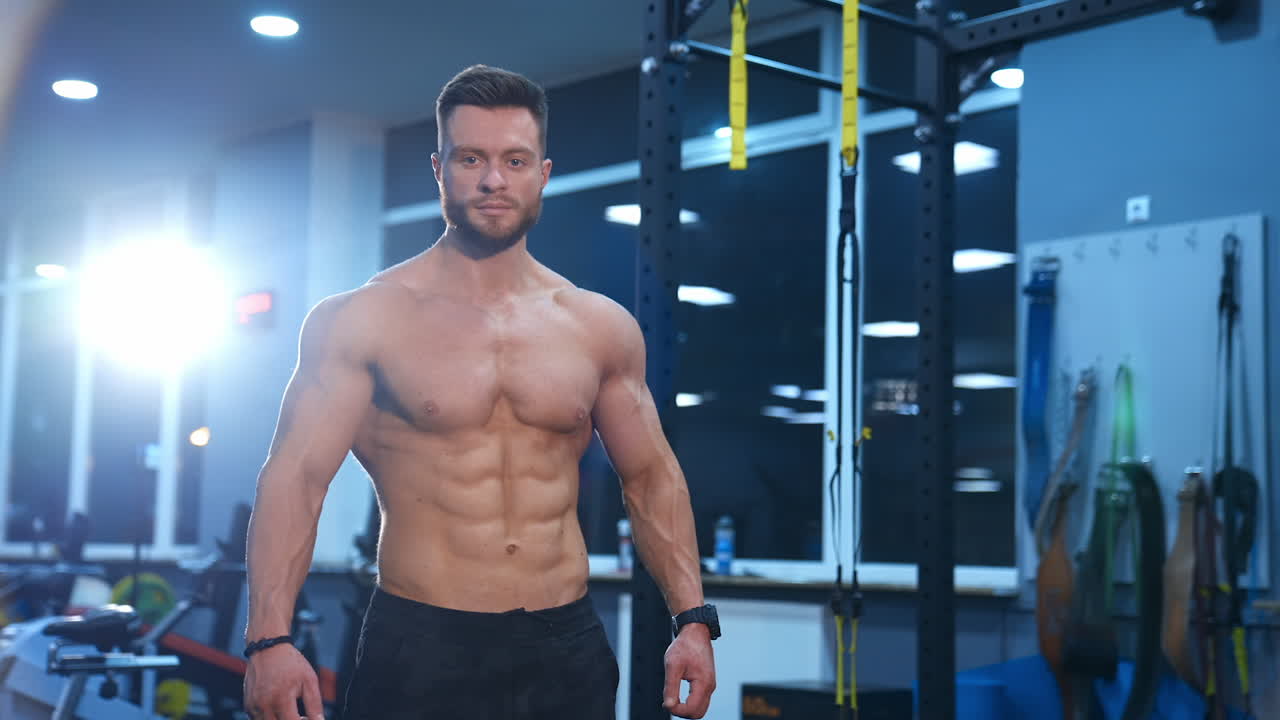 Muscular man posing in gym. Handsome male bodybuilder with beautiful powerful muscles posing in the gym