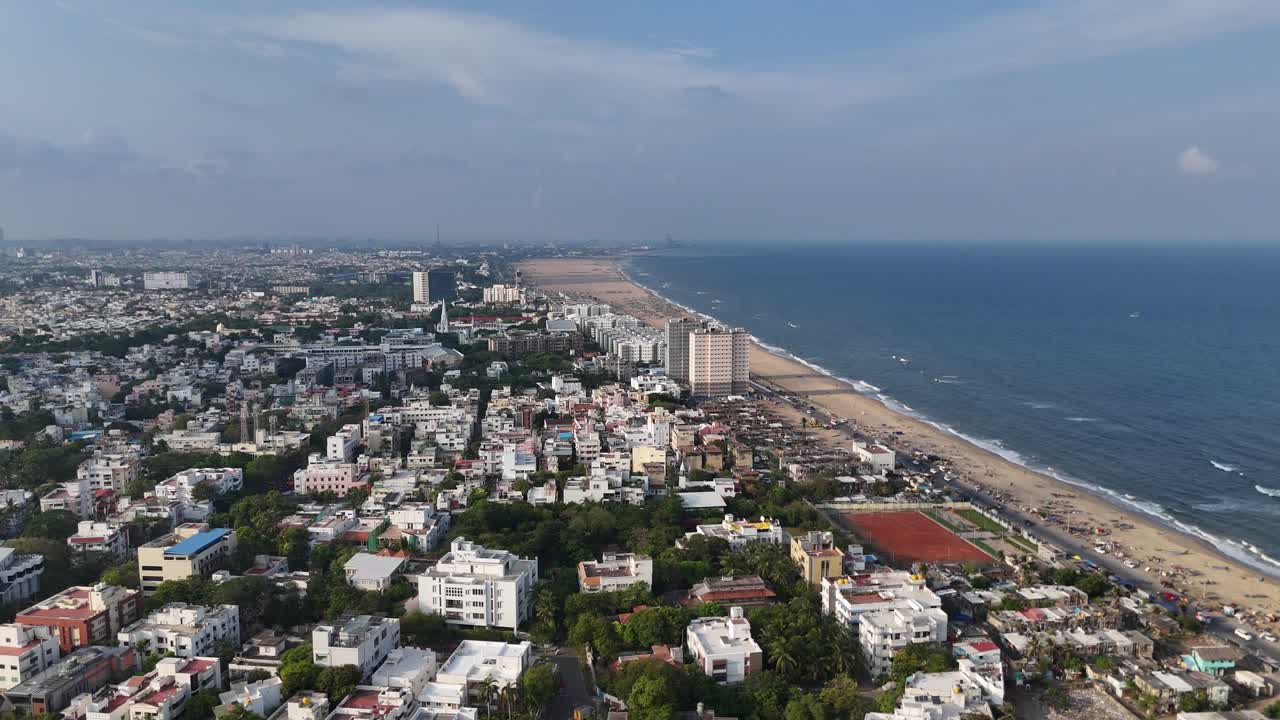 Aerial views of the bustling roads with identical buildings near marina beach in Chennai filled with crowd.