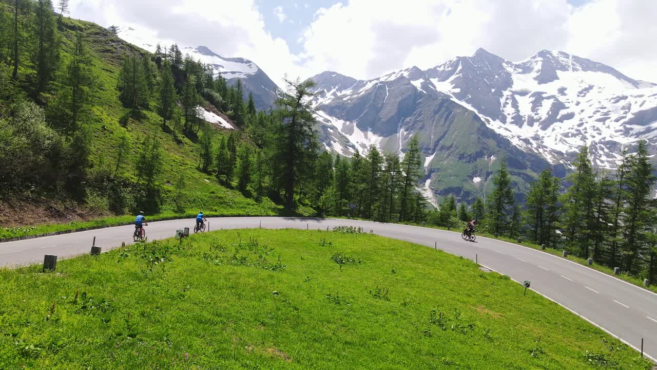 Mountain cyclists ride opposite directions on a winding alpine road in summer