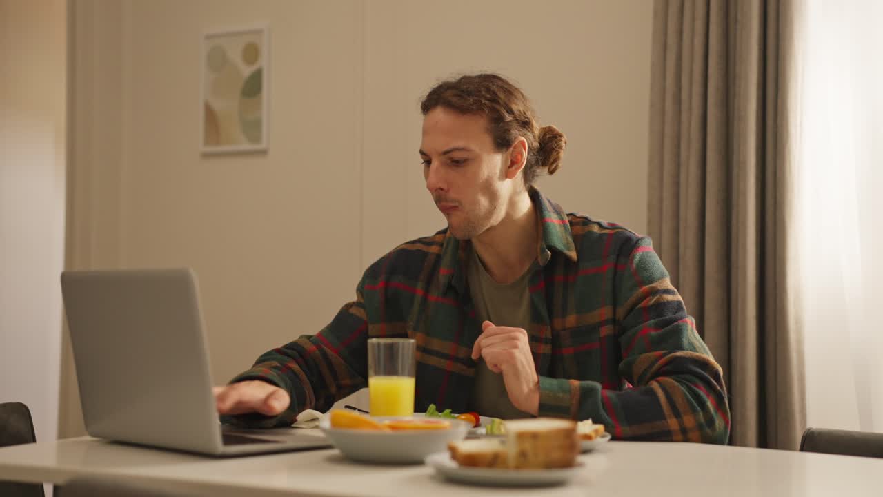 Man working on laptop during breakfast