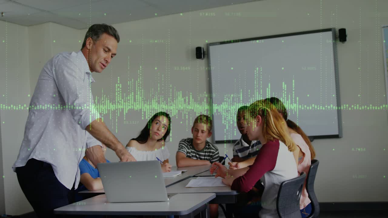 Teacher leaning over laptop, starting demo for class while students writing, green waveform moving