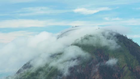 stunning view of a mountain surrounded by clouds during sunrise in the ijen volcano complex.