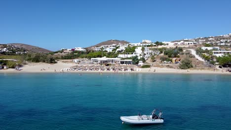 panoramic aerial orbit view over krios and marcello beach and an pleasure anchored boat, greece