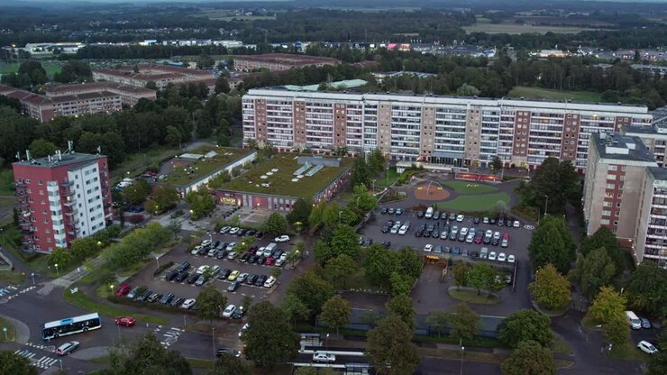 South Halmstad, Svezia - Grande complesso residenziale circondato da aree di parcheggio, alberi e strade trafficate al crepuscolo - Ripresa aerea con drone