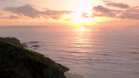 Drone shot of green forest lining secluded tropical beach at sunrise. Shot on tropical island. Beautiful natural secluded beach. Fly forward and slow pan down shot.
