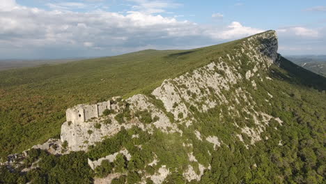 drone shot towards a ruined castle on the edge of a mountain in south of france.