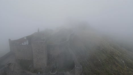 una espesa niebla sobre un castillo medieval es vista por un dron que vuela