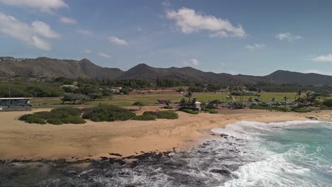 Ocean-view-of-Hawaiian-beach-with-mountains-in-background-and-blue-sky