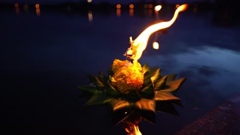 loy krathong festival - candle burning on krathong on the dark blue water