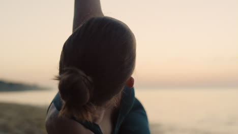 Sporty-woman-performing-utthita-trikonasana-on-beach-summer-morning-close-up.