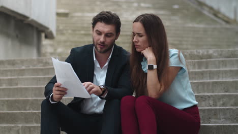 focused businesswoman and businessman working with financial documents at street