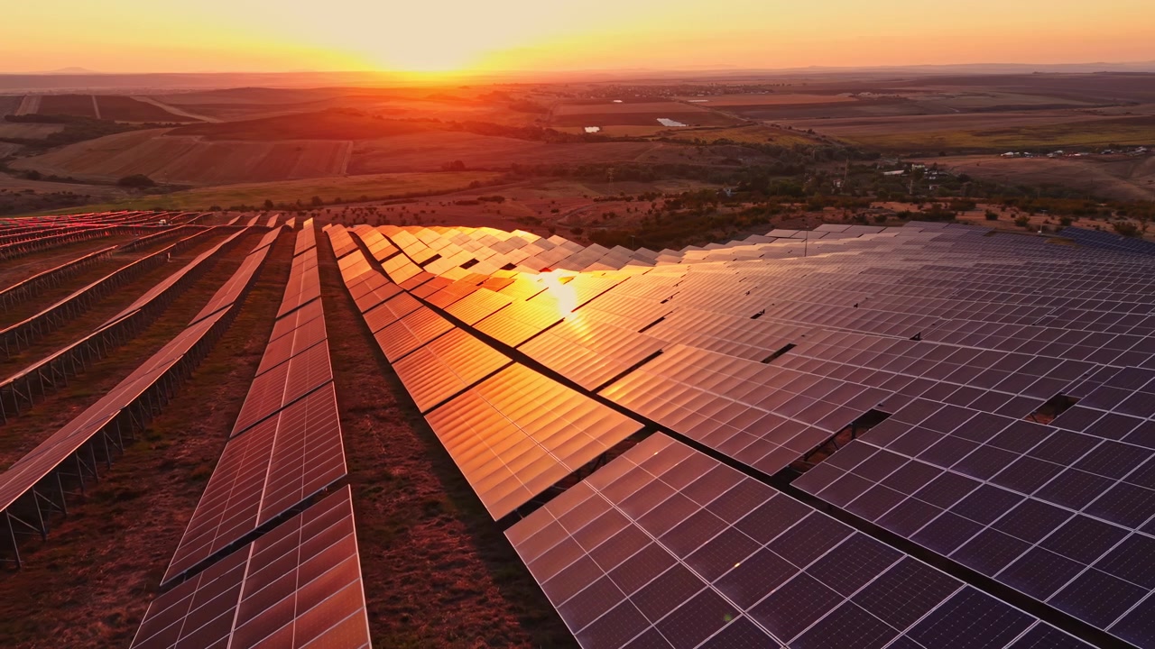Solpaneler fanger sollys under solnedgang over en stor mark på landet