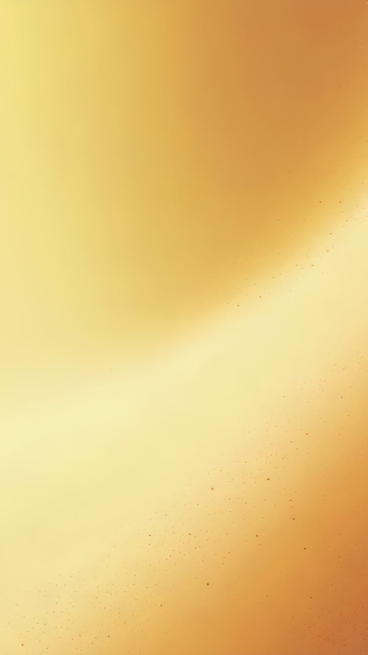 Vertical video: Shifting golden gradient in closeup after light shift, glowing and showing specks