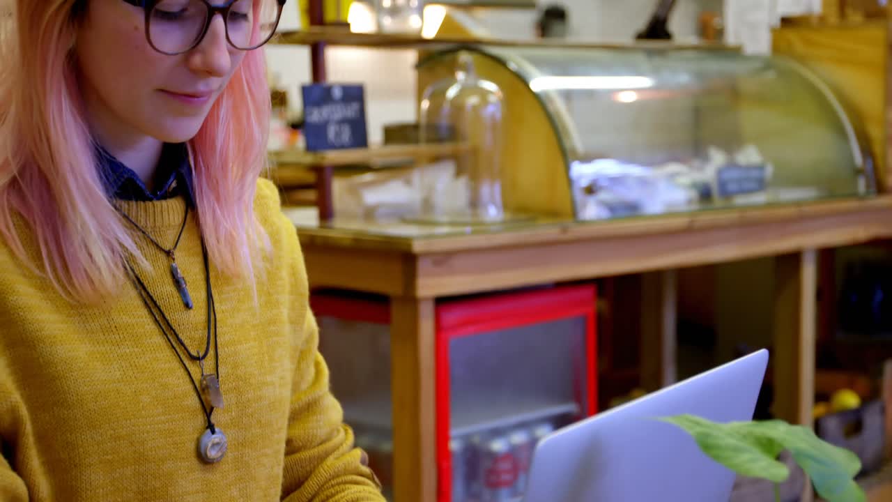 mujer joven usando computadora portátil en el café 4k