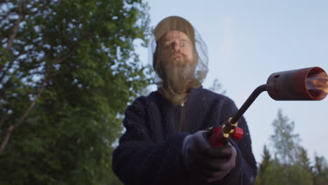 psycho man wearing mozzie head net use blowtorch to kill summer bugs, front pov