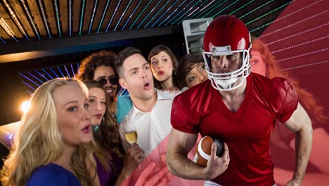 animation of male american football player over happy diverse male sport fans watching game at bar