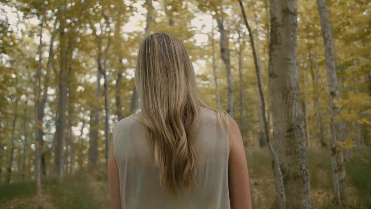 Femme blonde debout dans une forêt d'automne dorée