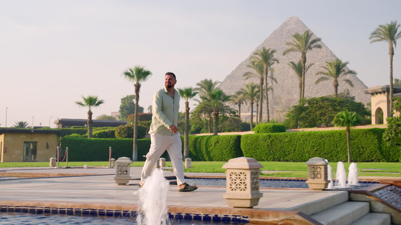 Man Walking On The Swimming Pool Of A Luxury Complex Hotel Near Giza Pyramids In Egypt. Tracking Shot