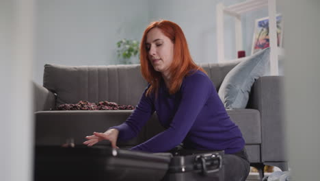 red-haired woman puts summer clothes into black suitcase