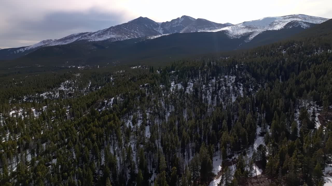 Faint trail winds through snow-patched woodland clearing at high altitude, Allenspark Colorado USA