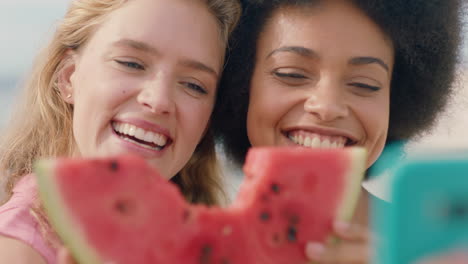 two beautiful women posing with watermelon taking photos using smartphone woman kissing friend on cheek happy girl friends sharing relationship on social media having fun on seaside 4k