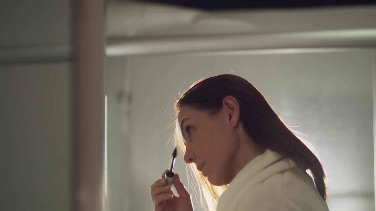 mujer morena poniéndose rímel en el baño por la mañana