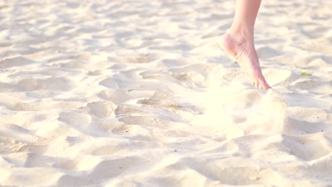 person walking barefoot and kicking sand on sunny beach in phuket