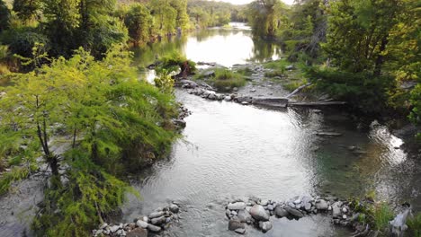 flying about 20 feet above river near recreational swimming area at sunset