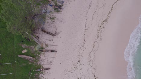 top down of pantai mandorak with clear blue water and fishing boats on shore, aerial