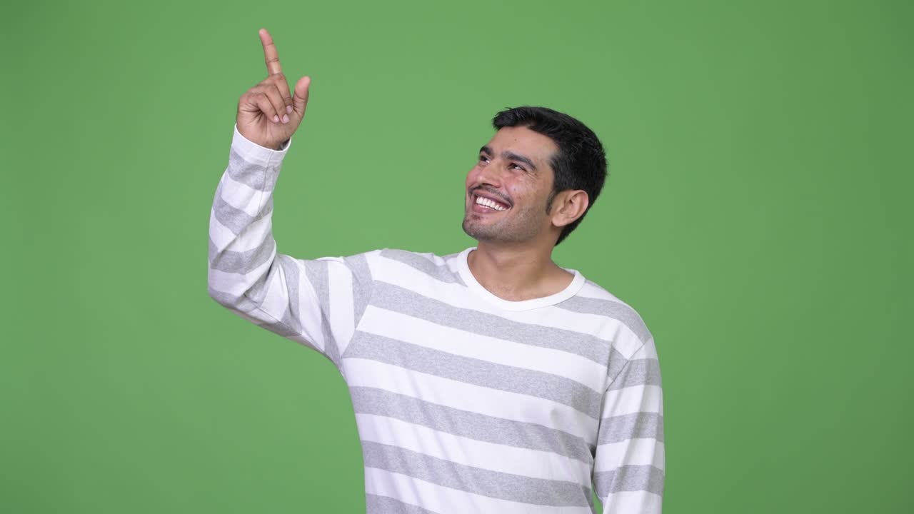 Young handsome Persian man pointing up