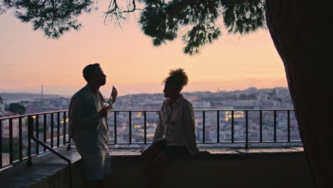 lovers silhouettes chatting at sunset viewpoint. gesturing man telling story