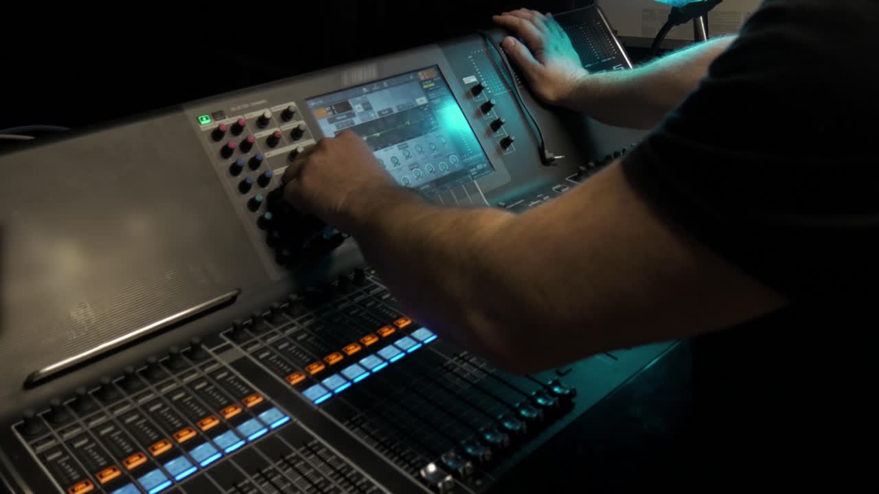 brazos de hombre operando una consola en un teatro