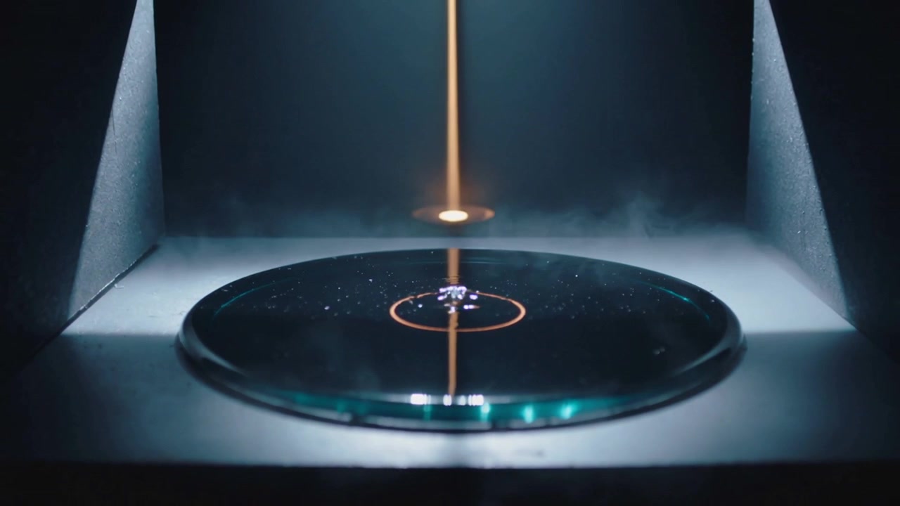 Brightening orange column depositing onto glass disc in lab, forming droplet within target ring