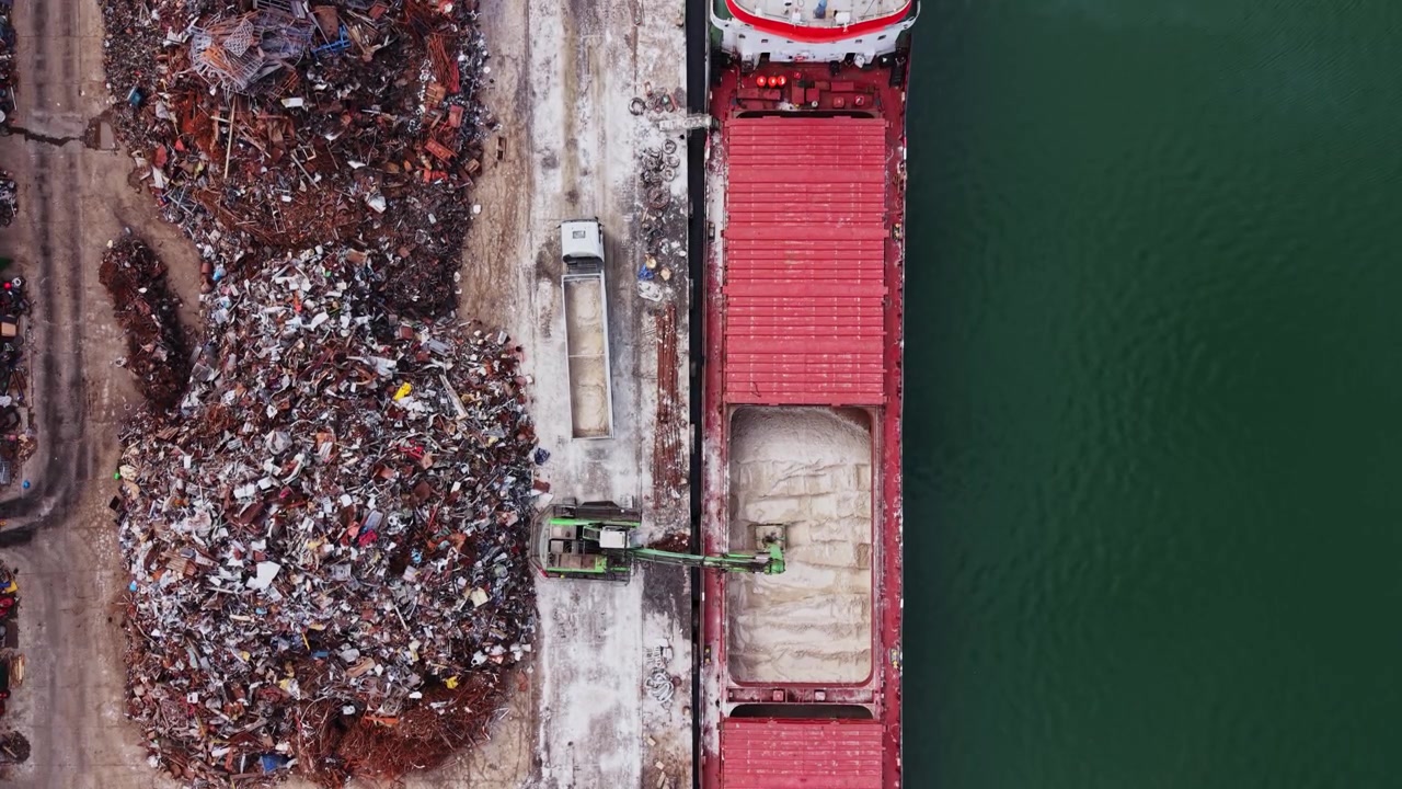 Materiali di scarto vengono caricati su una grande nave da carico al porto.