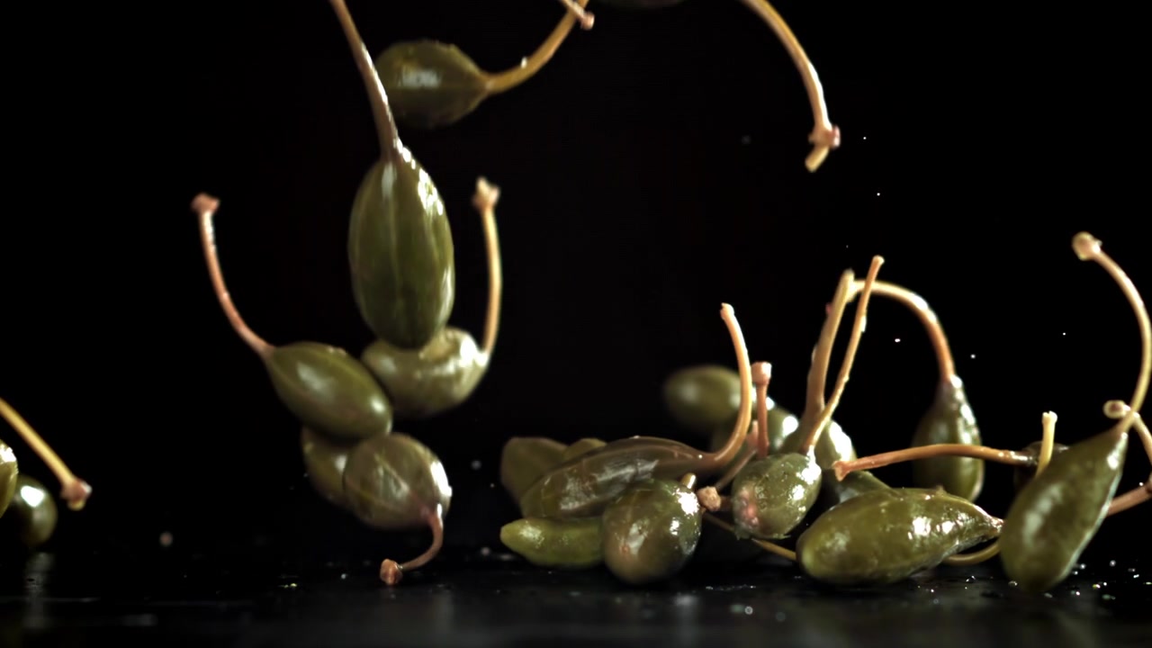 Slow motion di capperi che cadono su sfondo scuro