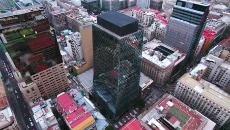 Aerial-orbit-of-a-diamond-shaped-glass-building-in-downtown-Santiago-Chile,-avant-garde-style-offices-with-modern-design