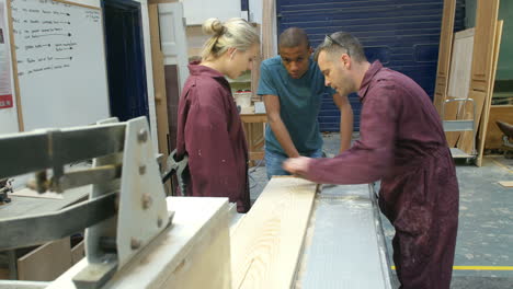 carpenter showing apprentices how to measure wood