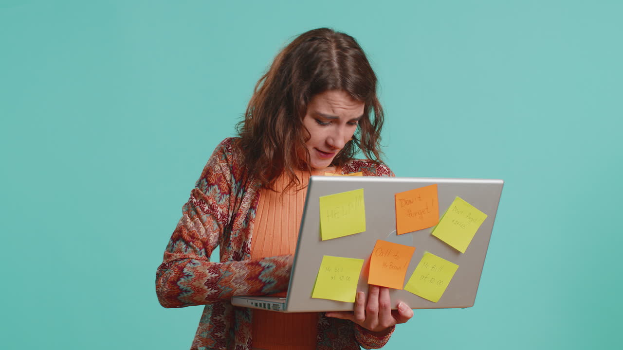 mujer independiente agotada con notas adhesivas pegadas usa portátil confundida por la gran carga de trabajo de rutina