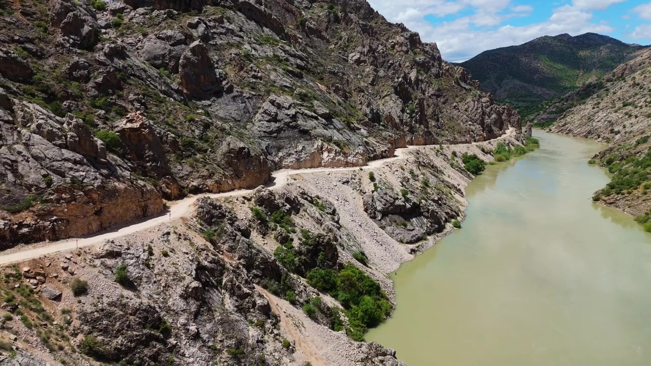 Perspectiva aérea volando a través del profundo Cañón Oscuro en Kemaliye, Turquía. Toma de dron siguiendo el curso del río Karasu con la legendaria Carretera de Piedra tallada a mano visible en el acantilado.