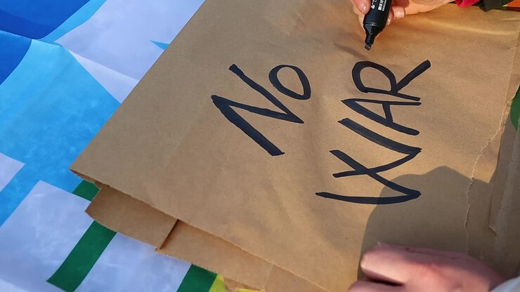 Kaukasisk pige skriver antikrigs-protestplakat over fredsflaget, zoom ind
