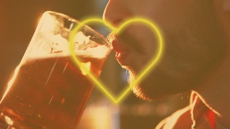 animation of yellow heart neon text over caucasian man drinking beer in bar