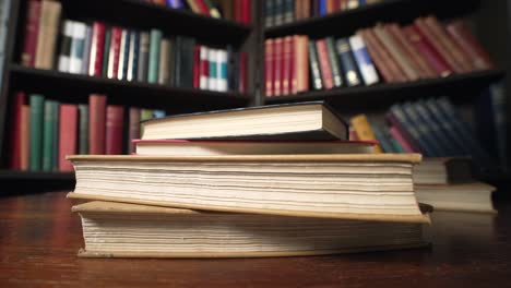 Books-are-dropped-one-by-one,-stack-of-books-on-table-in-classic-library-of-education