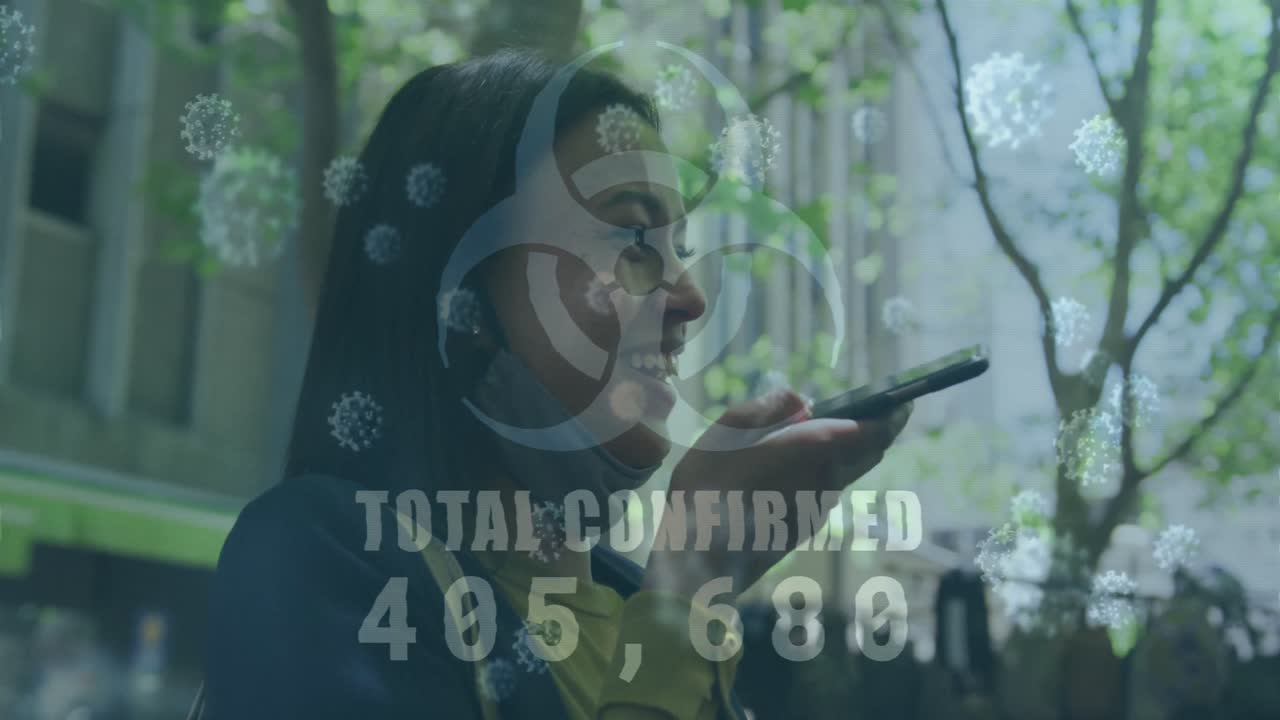 Biohazard symbol and increasing cases against woman with lowered face mask talking on smartphone