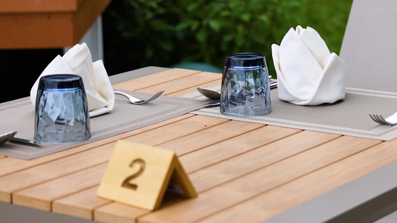 A neatly arranged table with glassware and napkins in a Phuket restaurant, captured in natural lighting